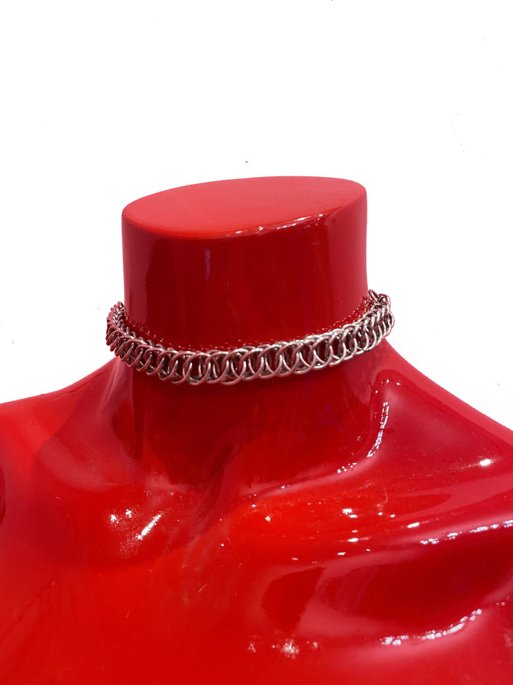 A close-up of a simple yet stunning chain mail choker, featuring a delicate and intricate weave. The choker rests gracefully against a neutral backdrop, showcasing its elegant and versatile design.