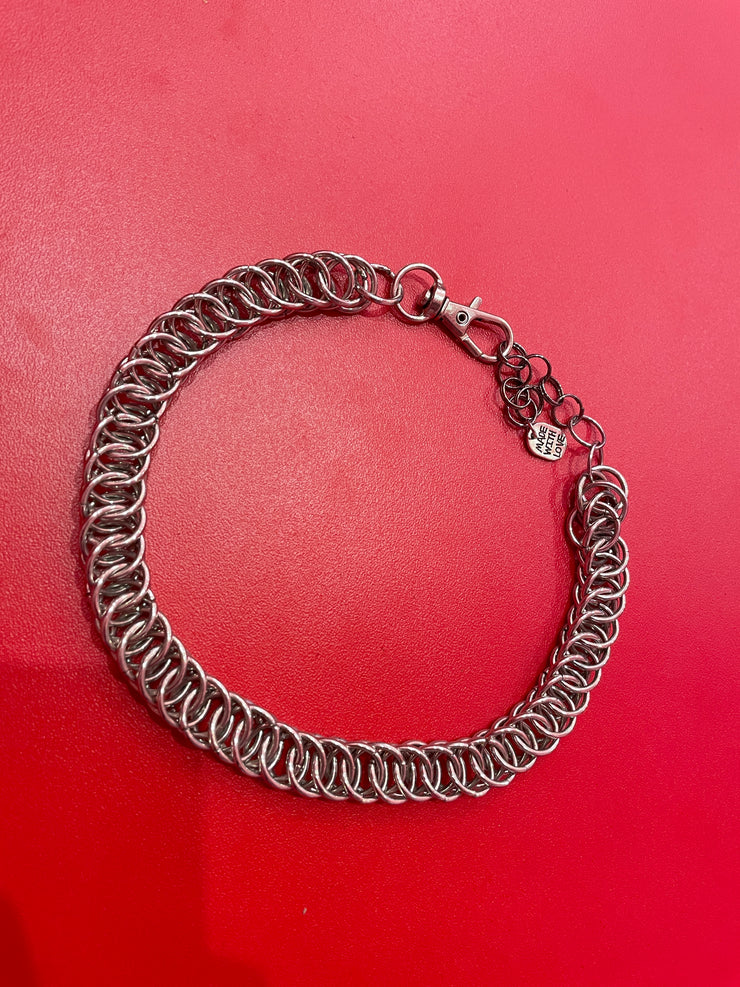 A close-up of a simple yet stunning chain mail choker, featuring a delicate and intricate weave. The choker rests gracefully against a neutral backdrop, showcasing its elegant and versatile design.