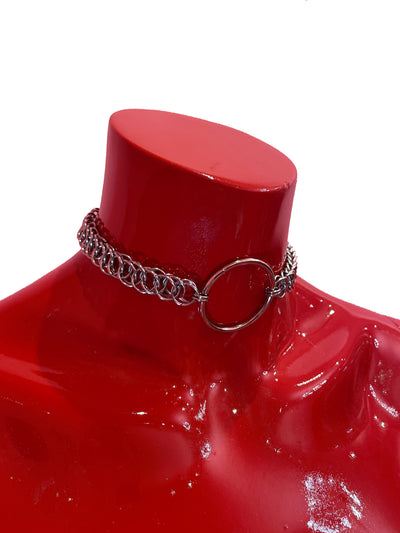 A close-up of a simple silver chain choker with a bold ring at the center. The sleek, minimalist design rests elegantly against a neutral backdrop, highlighting its refined and timeless appeal.