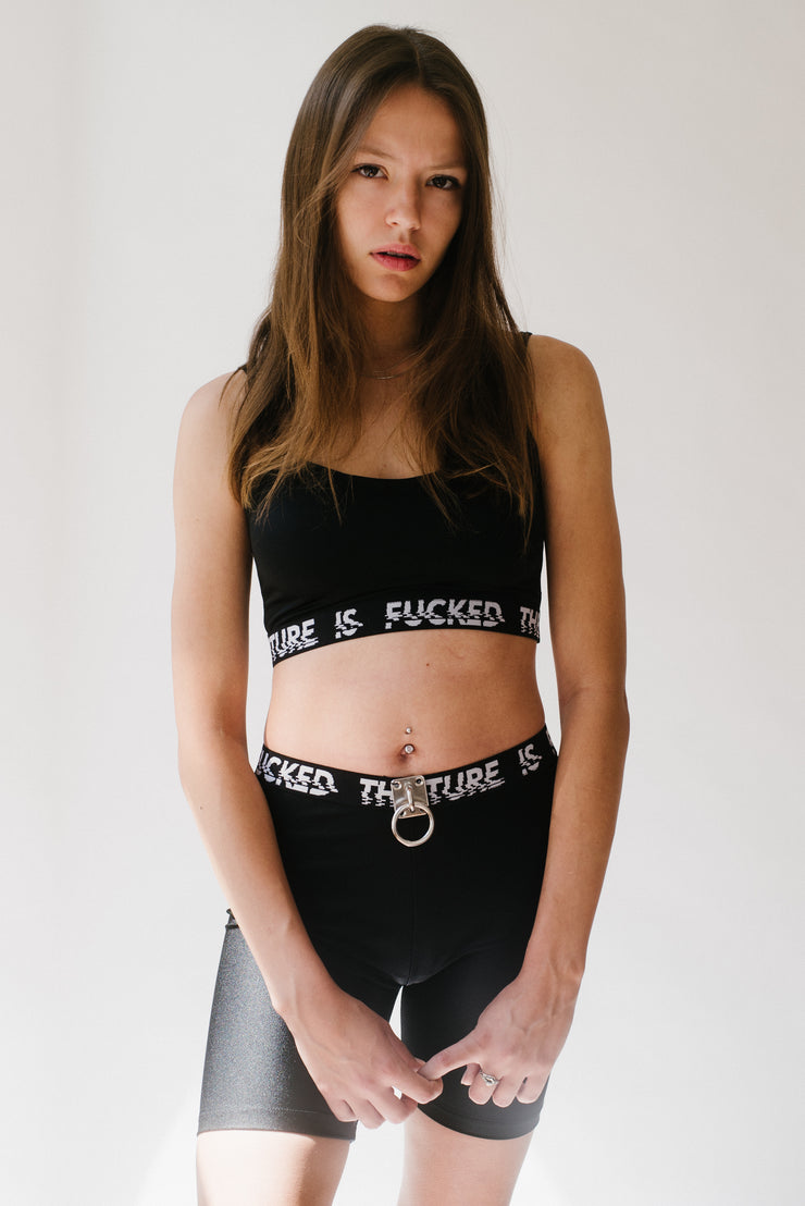 Black biker shorts with an "THE FUTURE IS FUCKED" elastic band and a silver hardware detail.