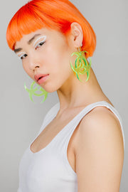 Neon yellow statement earrings in a toxic symbol shape.