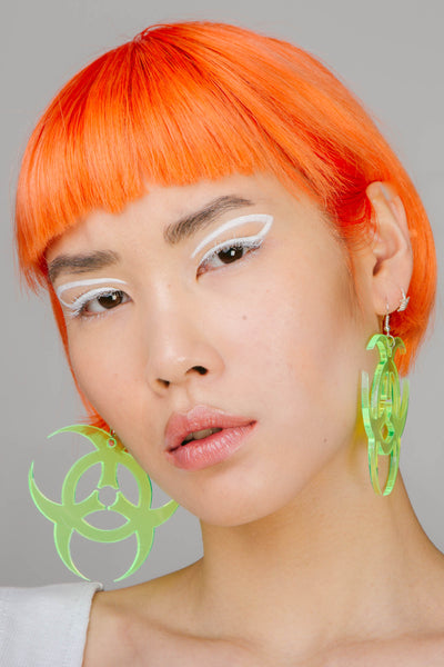Neon yellow statement earrings in a toxic symbol shape.