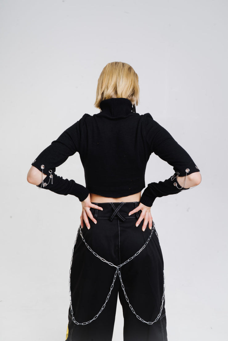 Black long sleeve top with chain closures on the sleeves.